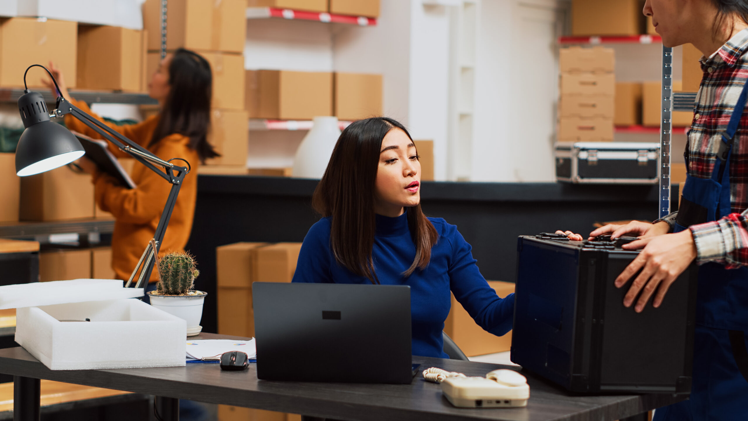 Small business owner looking at logistics on laptop, planning startup management and using stock logistics. Young woman working as entrepreneur in storage room warehouse. Tripod shot.